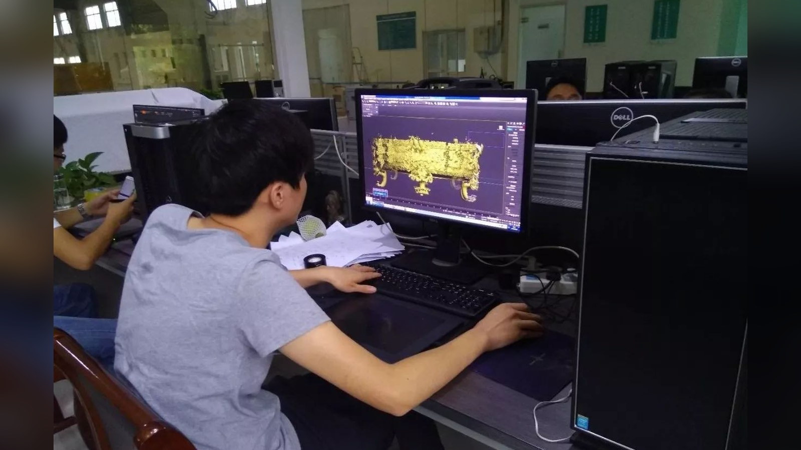 An operator viewing a three-dimensional model of an ornate vessel on a computer screen.