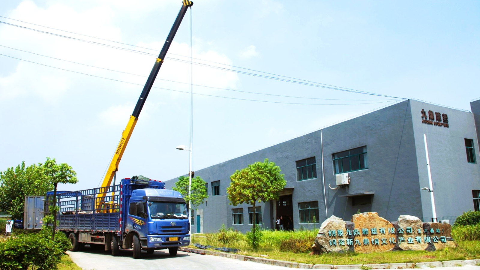A truck and mobile crane outside a fabrication workshop.