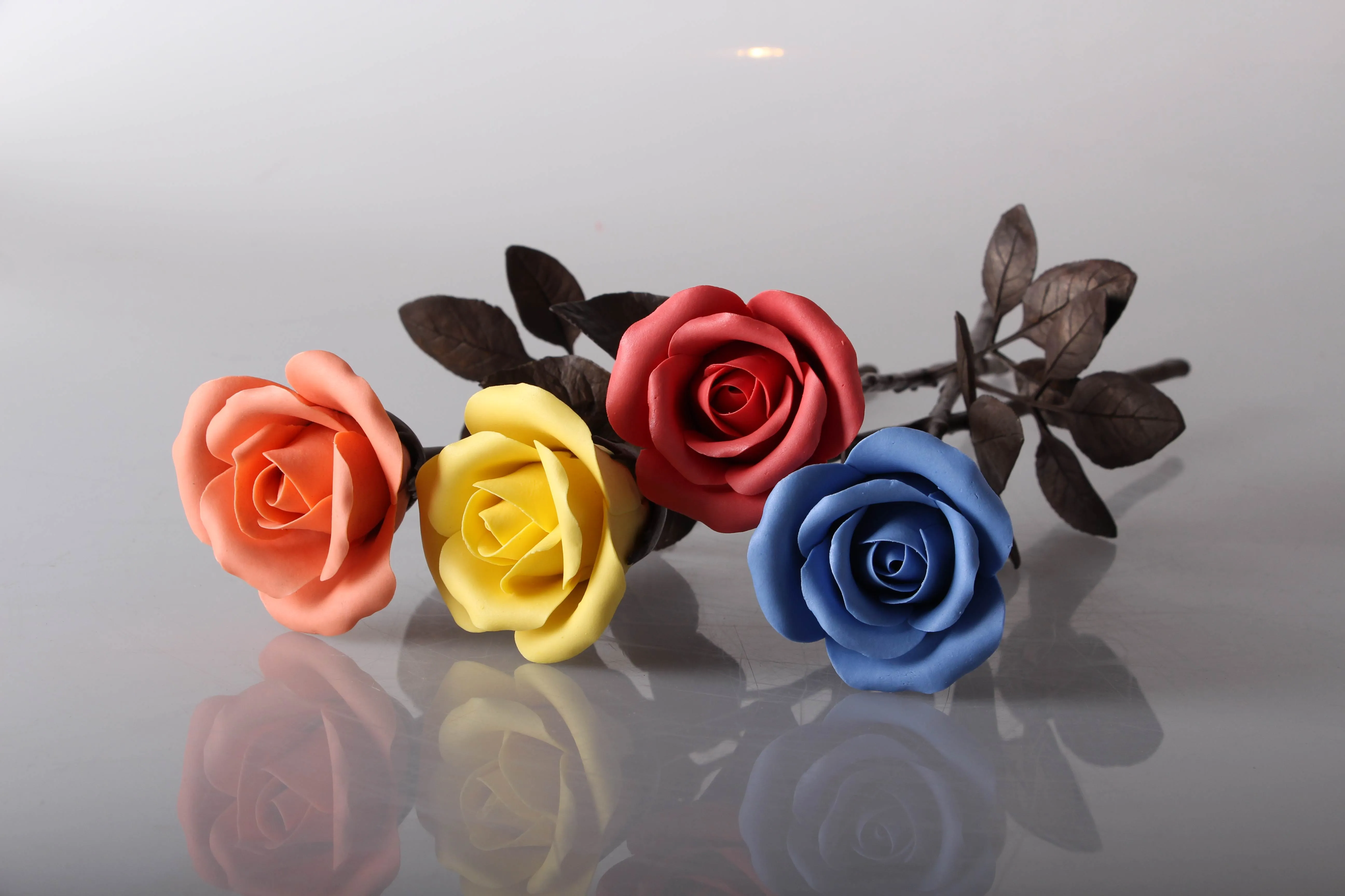 Sculptural rose with multicolored ceramic petals and a brass stem and leaves