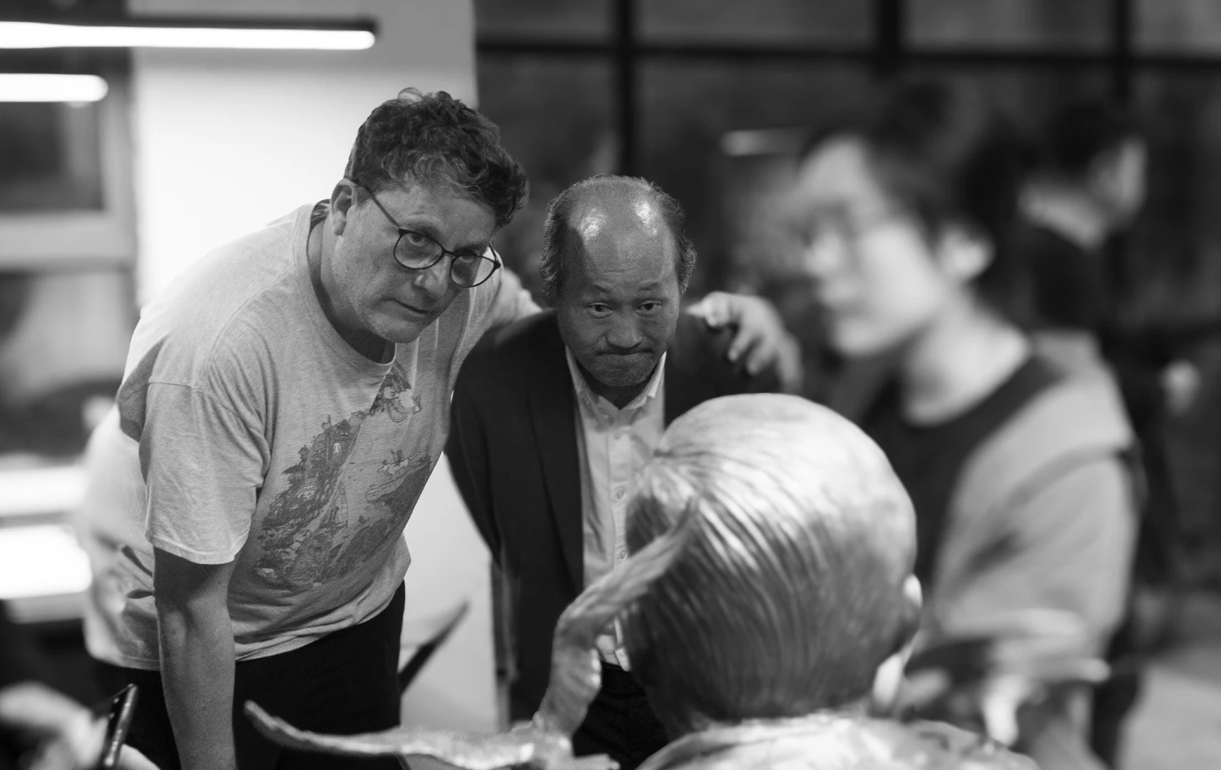 Visitors examining a sculpture in a black-and-white photograph.