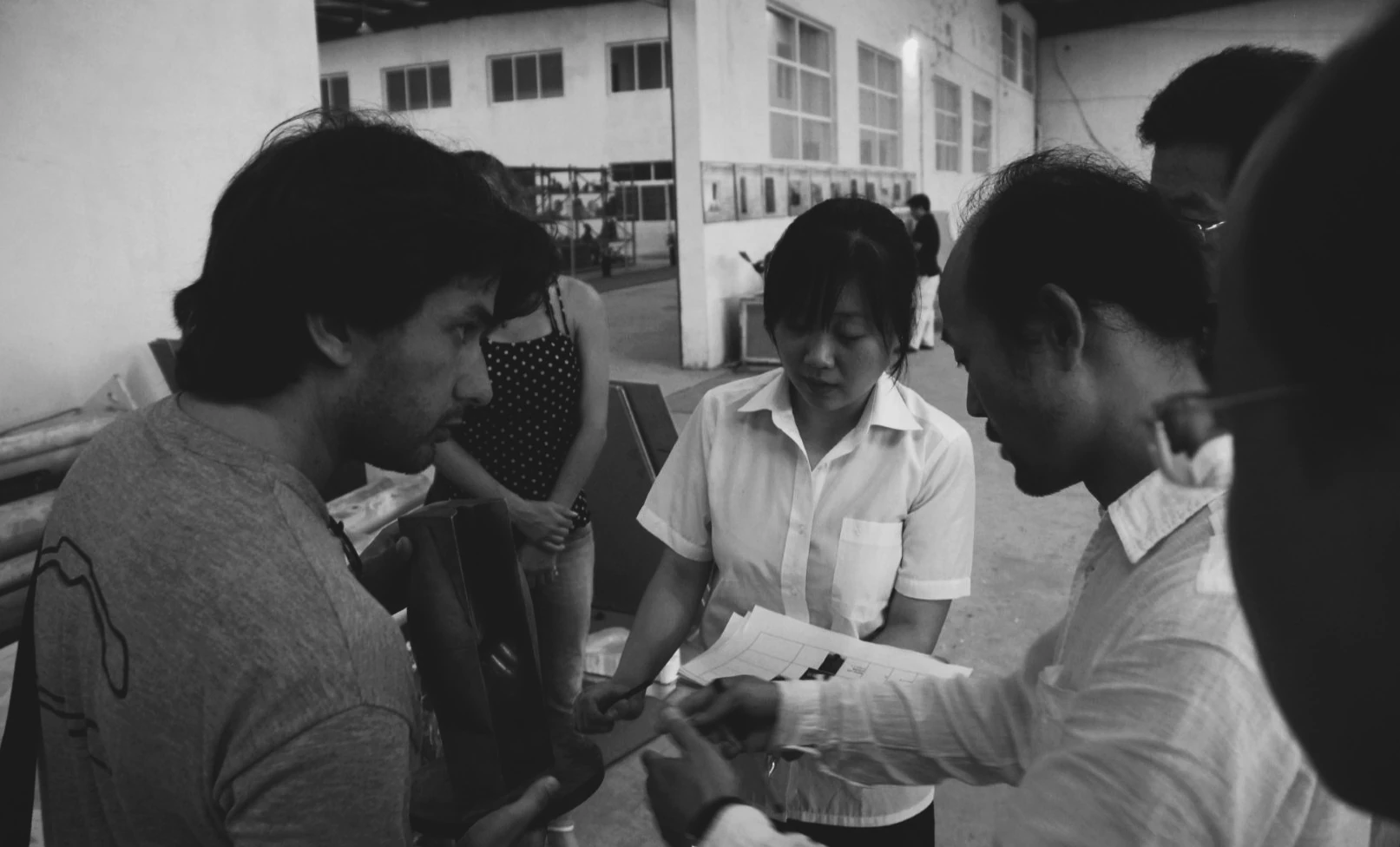Black-and-white photograph of a group discussing a model in the workshop.