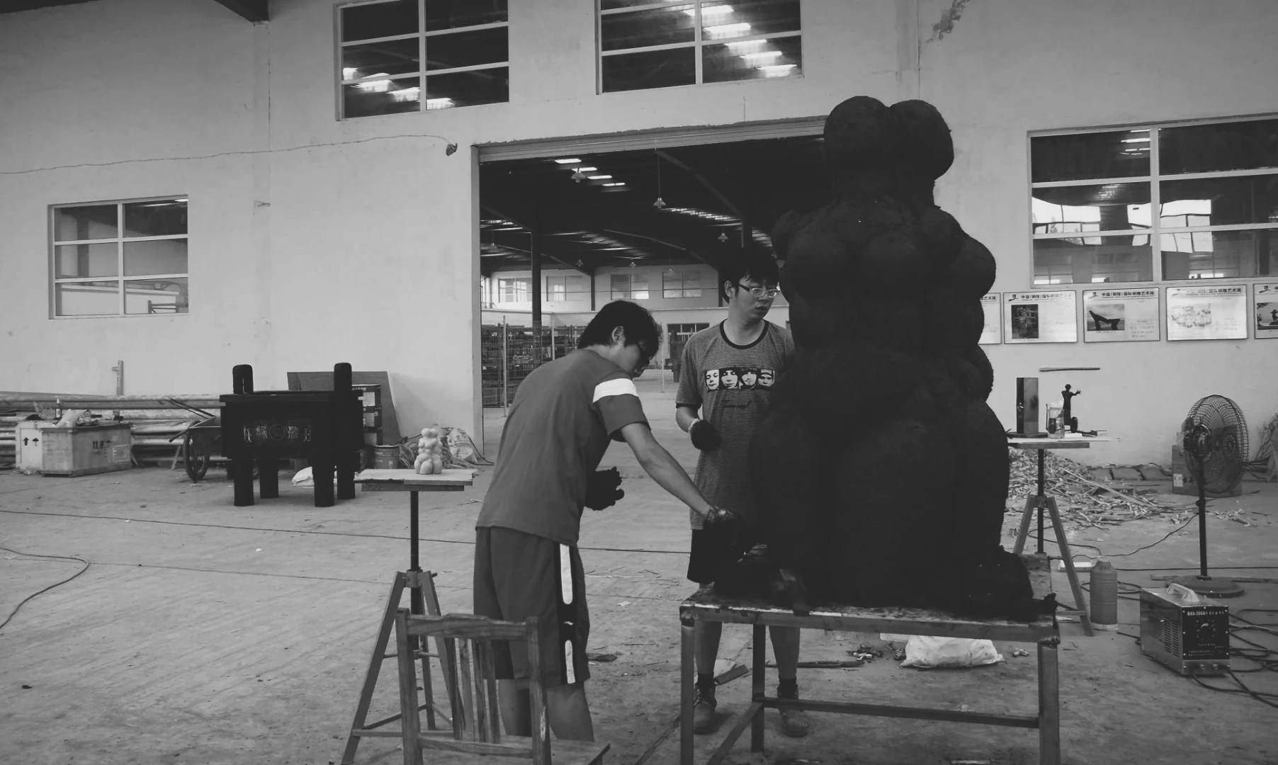 Black-and-white photograph of people working beside a large model.