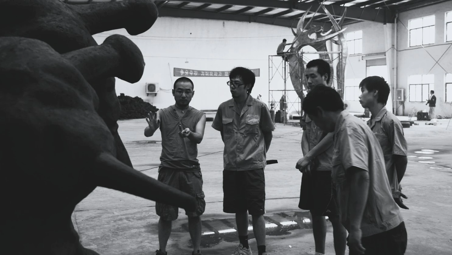 Black-and-white photograph of a group reviewing a sculpture model.
