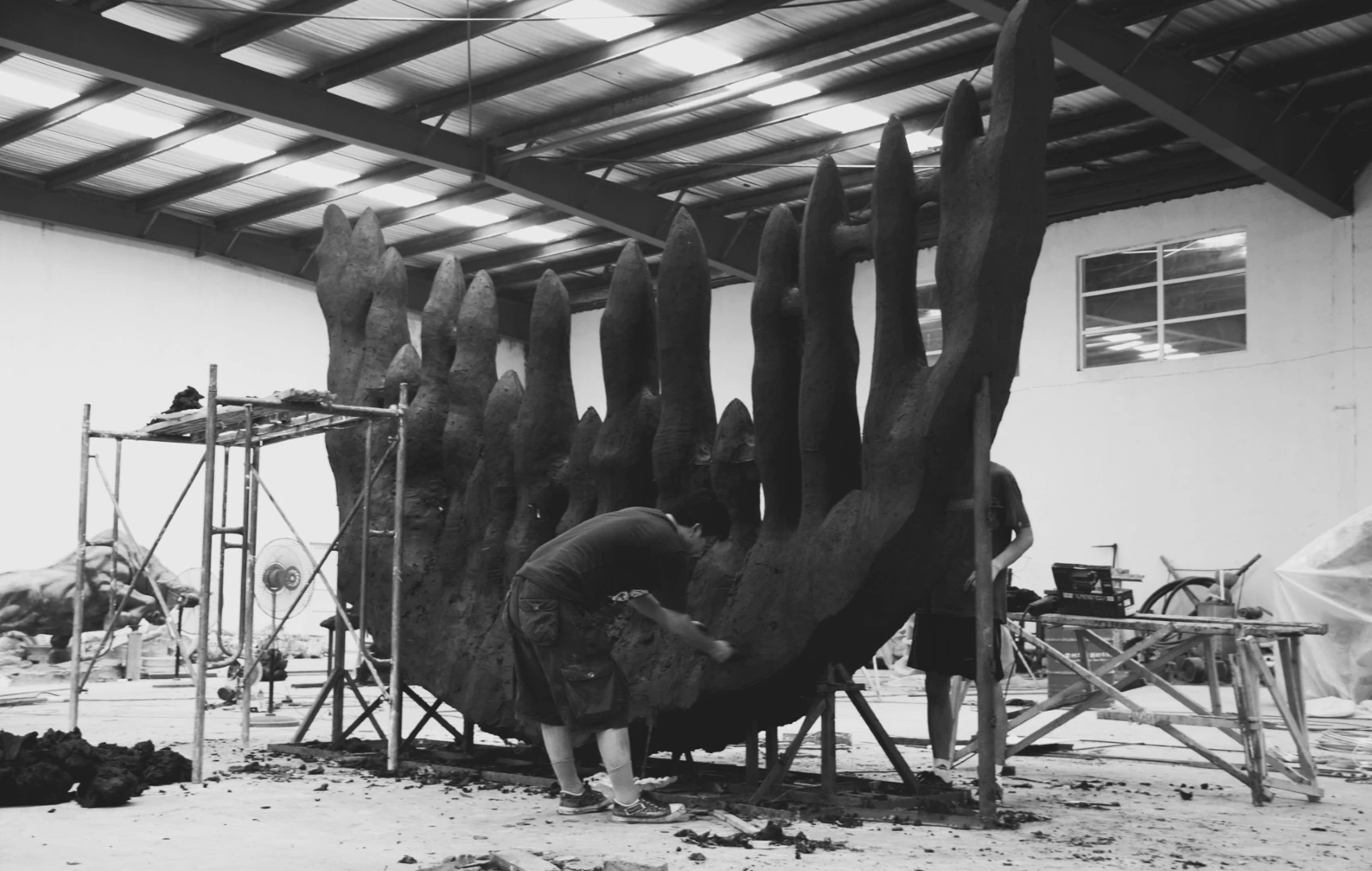 Black-and-white workshop photograph of a large sculptural form under construction.
