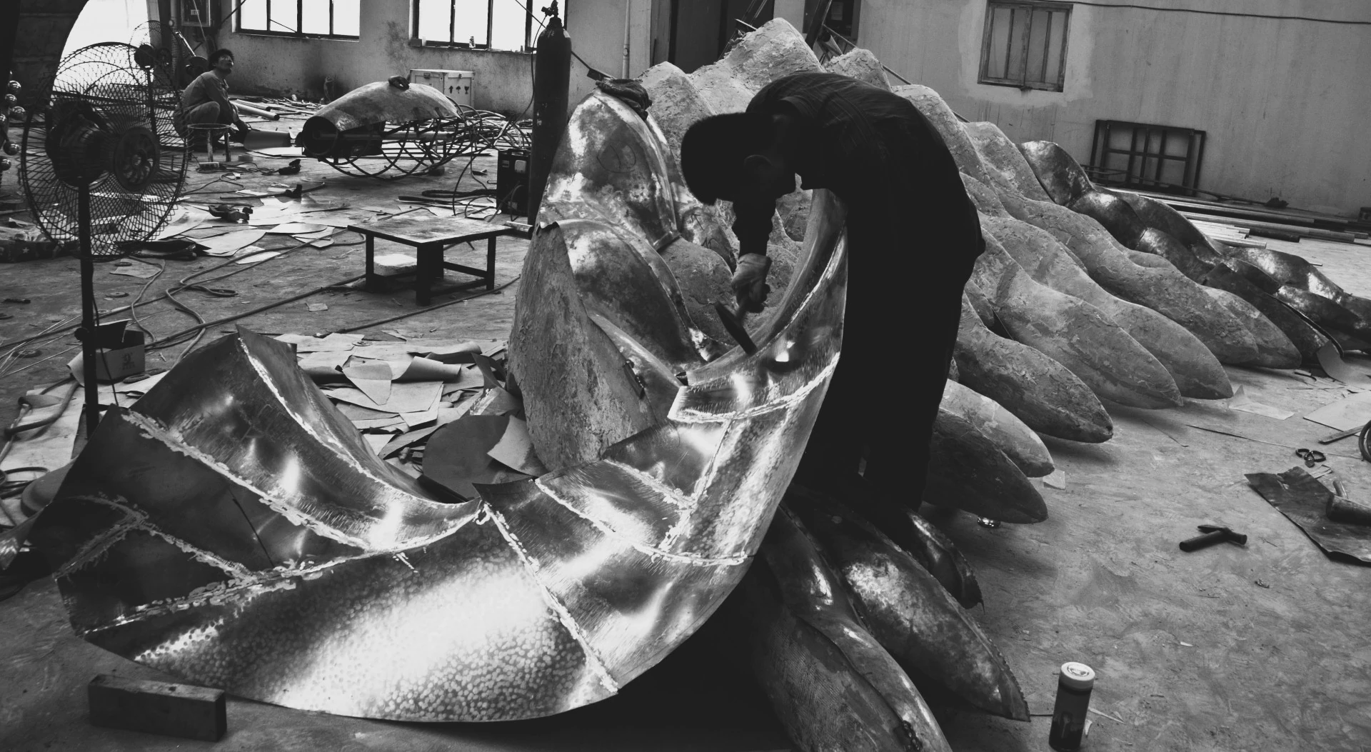 Black-and-white photograph of a maker working on a large metal component.