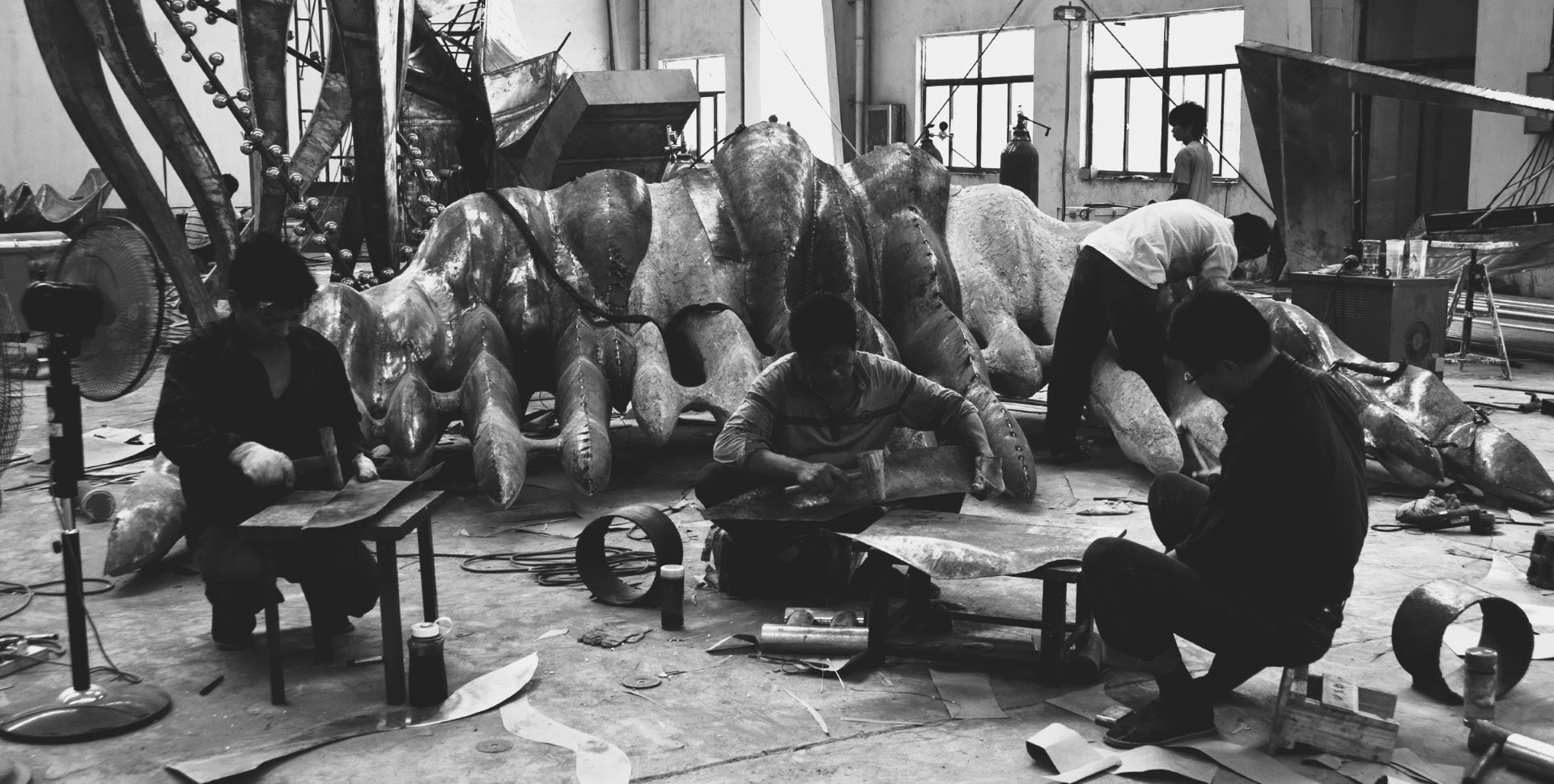 Black-and-white photograph of makers finishing sculpture components.