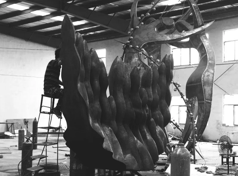 Black-and-white photograph of work on a large sculpture and its internal structure.