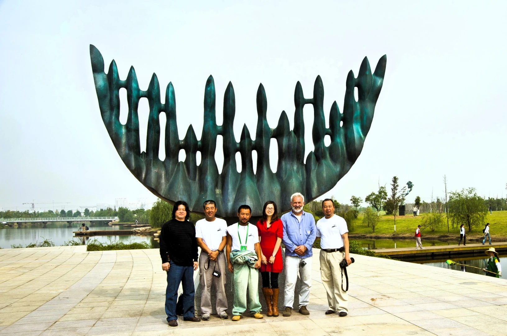 A group stands in front of a completed outdoor sculpture.