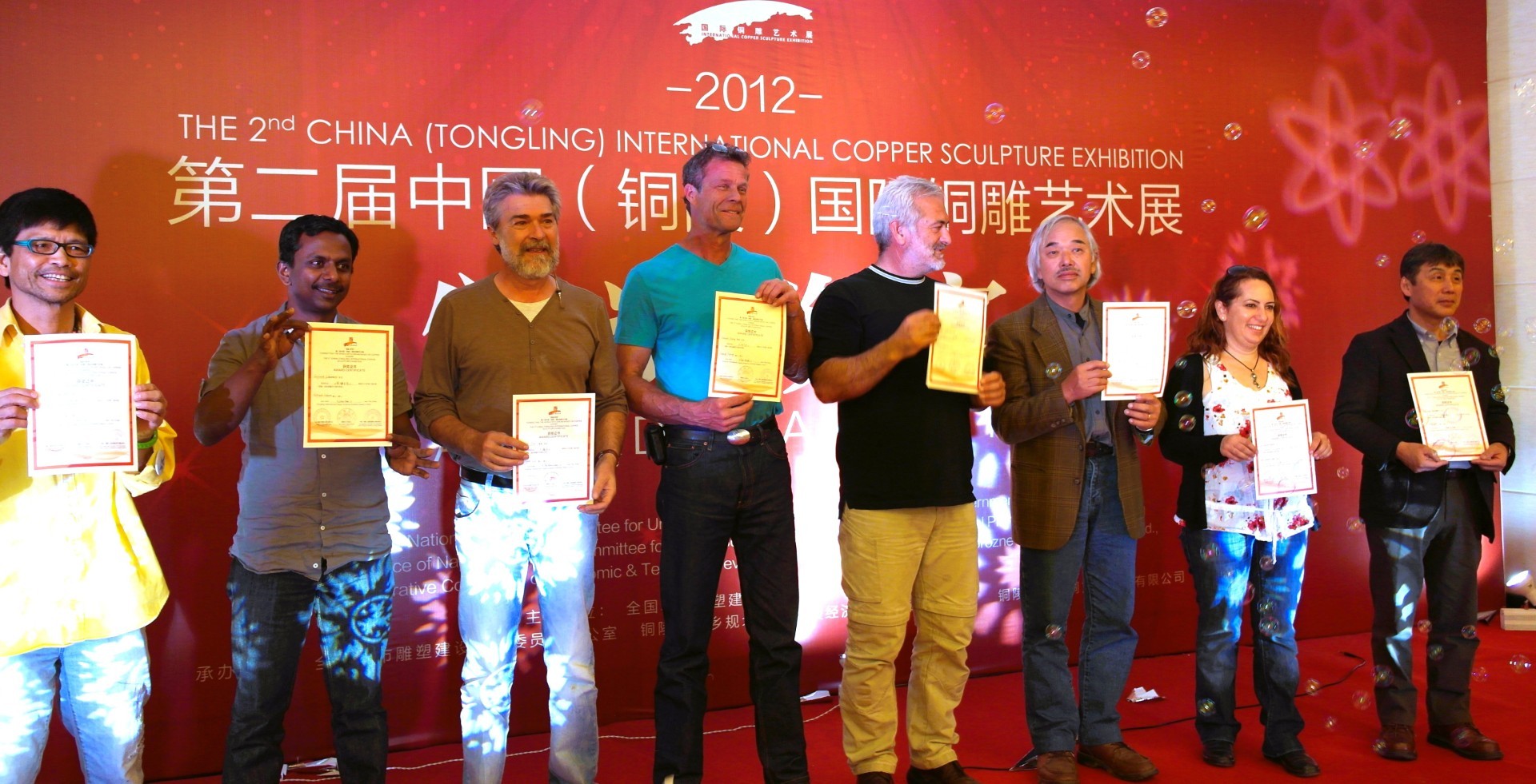 Participants hold certificates on stage at the 2012 sculpture exhibition.