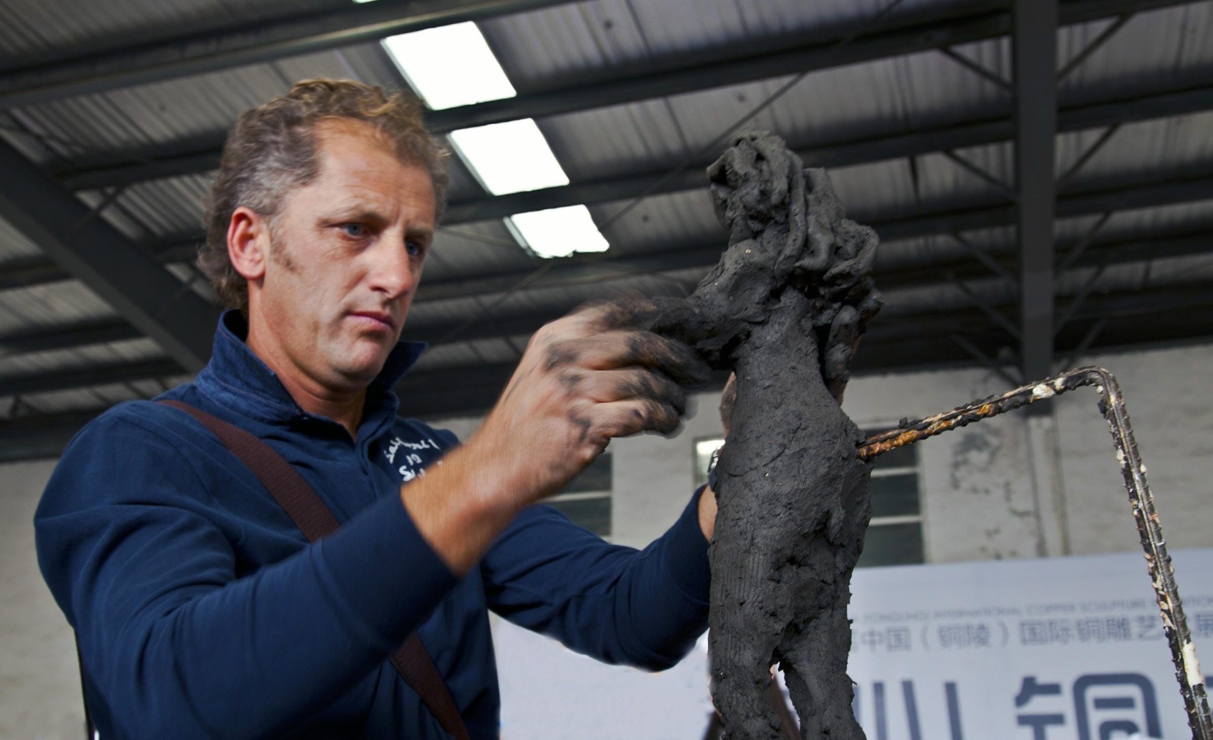 An artist shapes a clay sculpture inside the workshop.