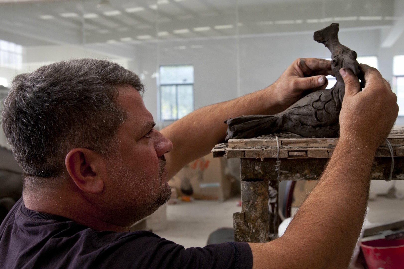 An artist refines a small reclining figure model.