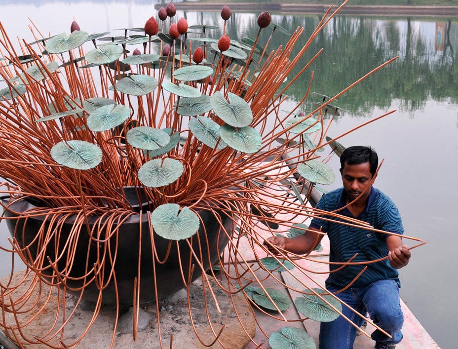 A worker develops a branching sculpture with copper-coloured rods and circular elements.