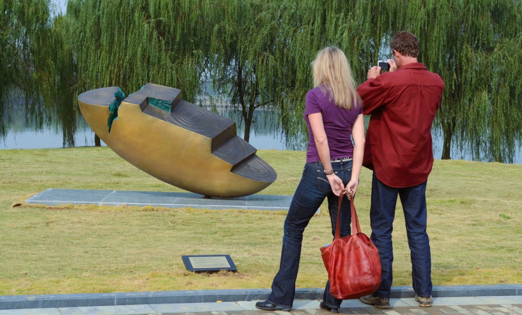 Two participants look towards an abstract sculpture beside the water.