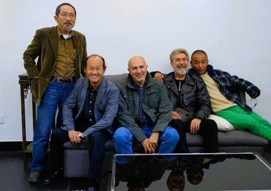 Five participants pose together around a bench.