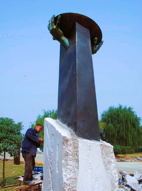 A tall sculpture and pedestal during installation.