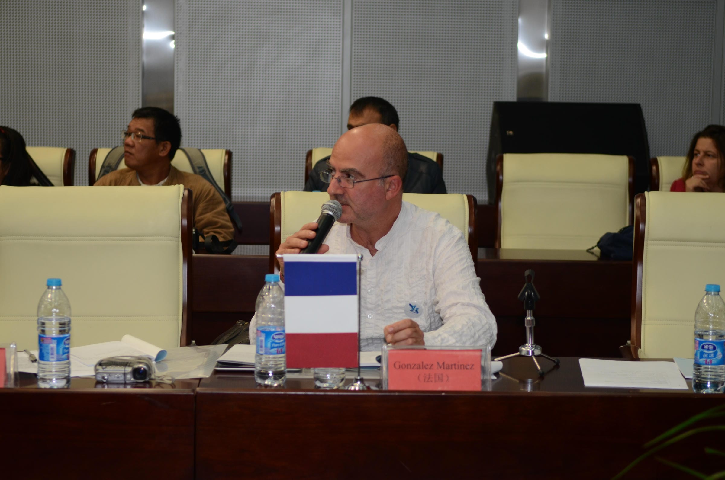 A participant addressing the meeting with notes and a microphone.
