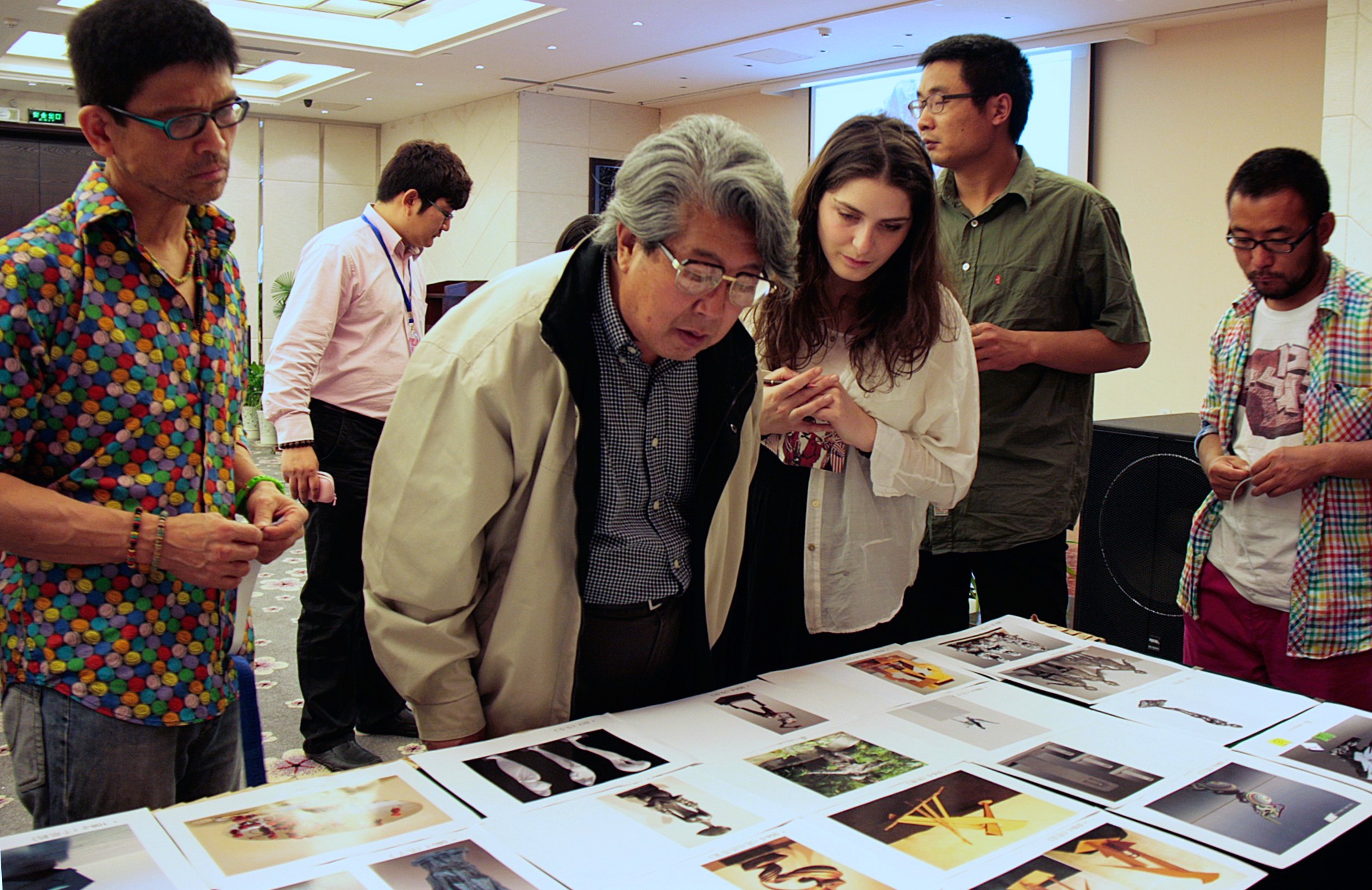 Participants examine photographs and project material spread across a table.