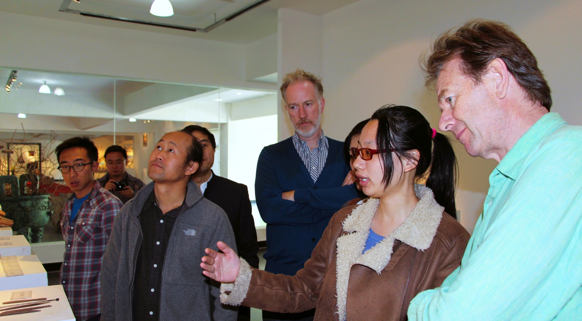 Visitors and Xinjiuding staff in conversation in the gallery.
