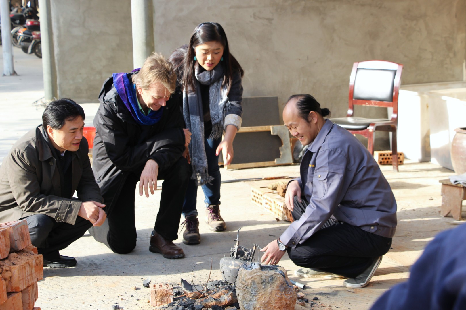 Visitors watching a demonstration beside materials and tools in the workshop.