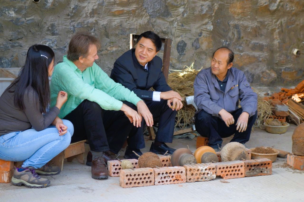 An interview taking place beside a small furnace and workshop materials.