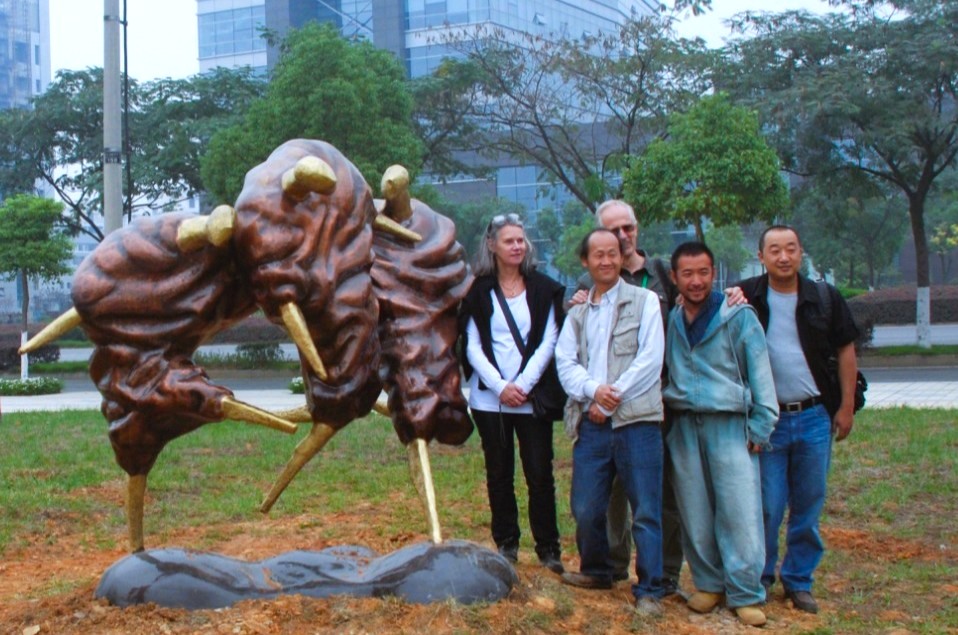 A group standing beside a bronze sculpture outdoors.