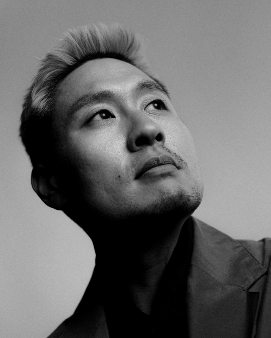 Black and white portrait of a man with short, light hair wearing a dark turtleneck and jacket.