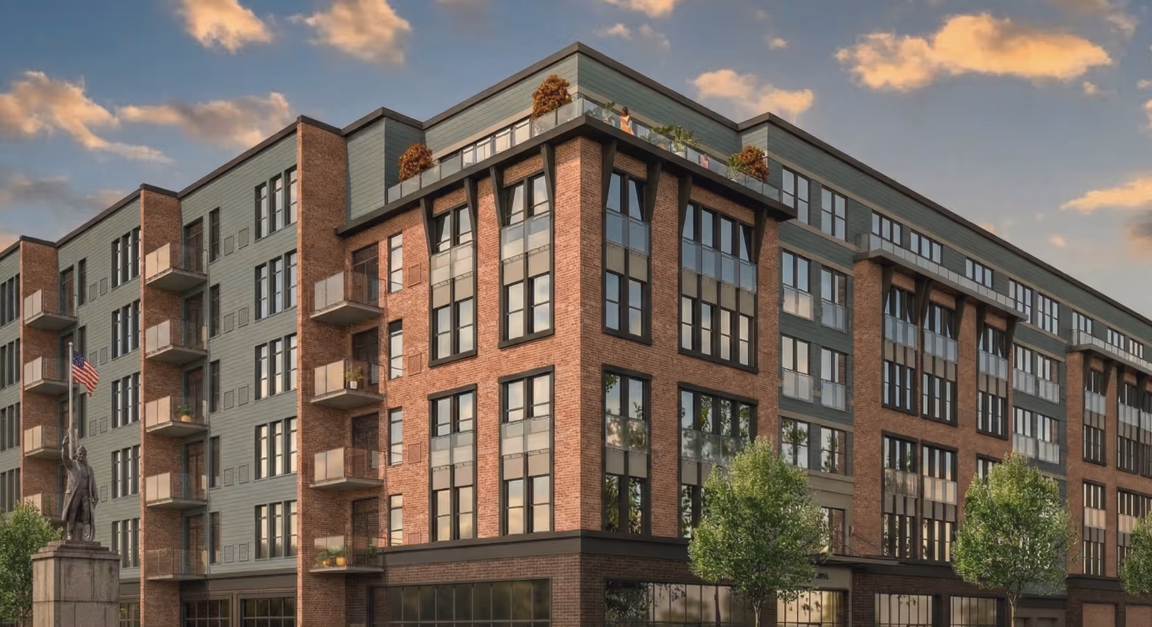 Modern brick and glass residential building with balconies, rooftop plants, and a statue holding an American flag.