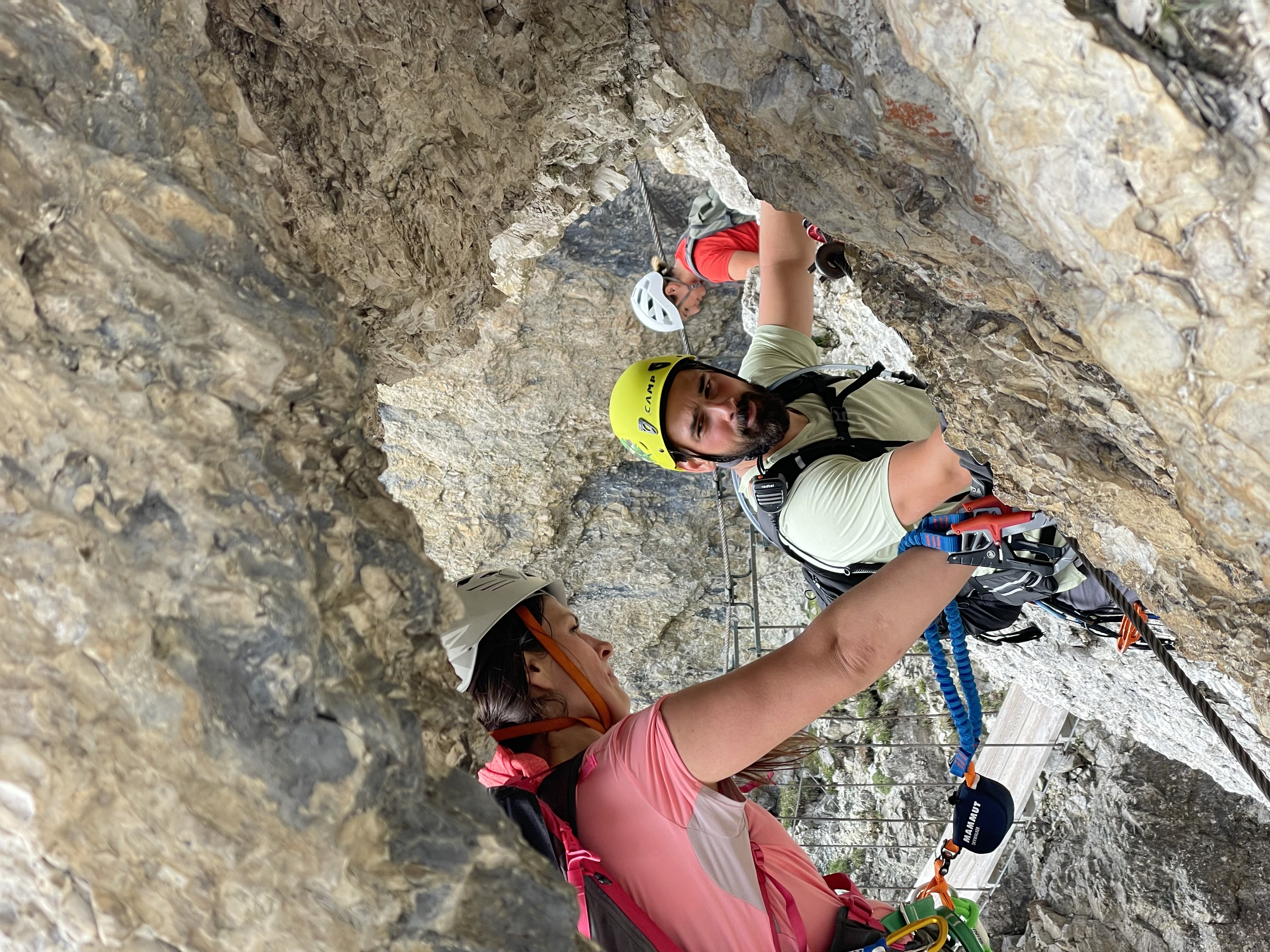 Guide watching a client's movement on a via ferrata route, both secured to a steel cable