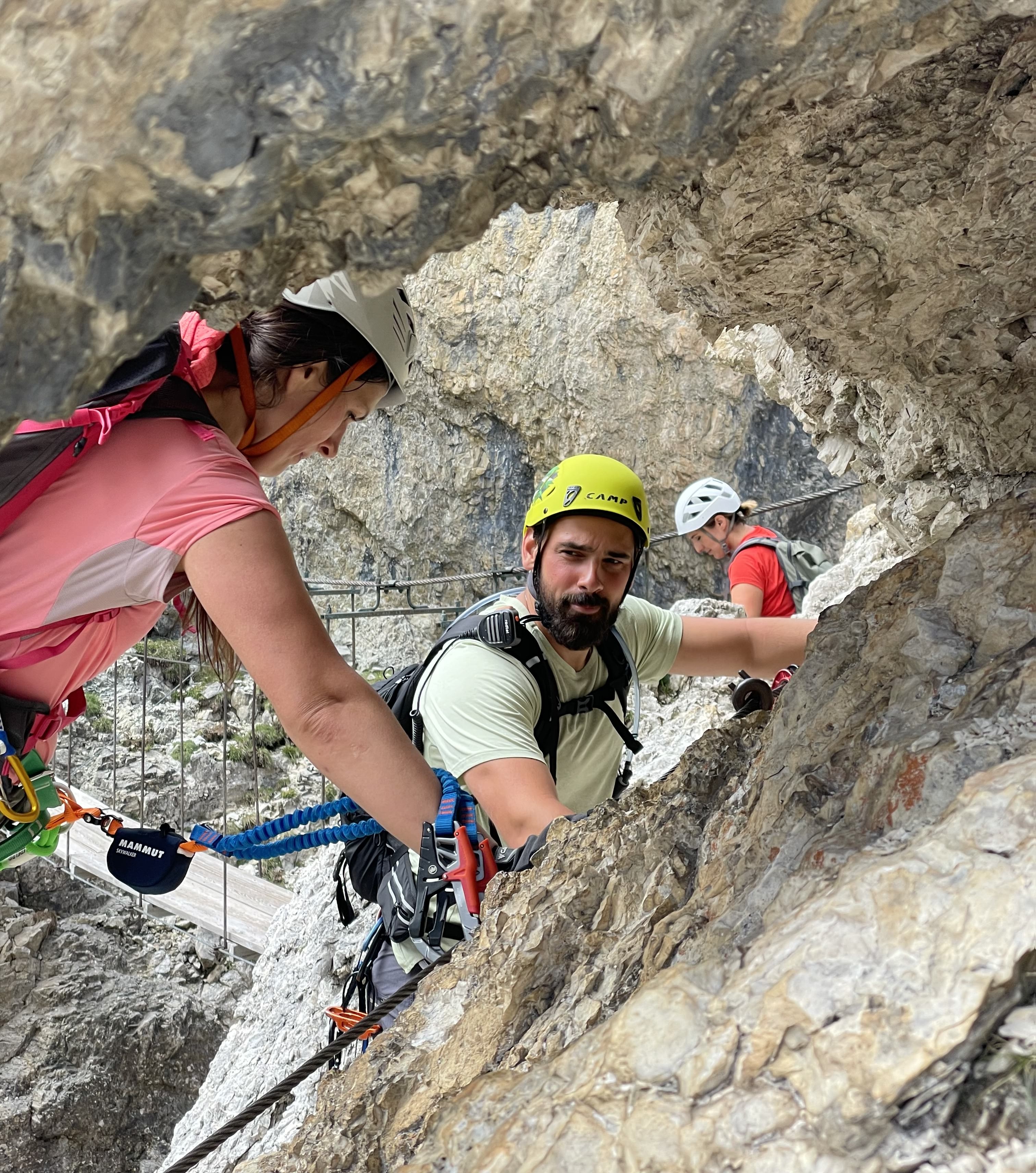 Guide watching a client's movement on a via ferrata route, both secured to a steel cable