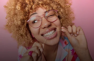 ragazza che si lava i denti con il filo interdentale