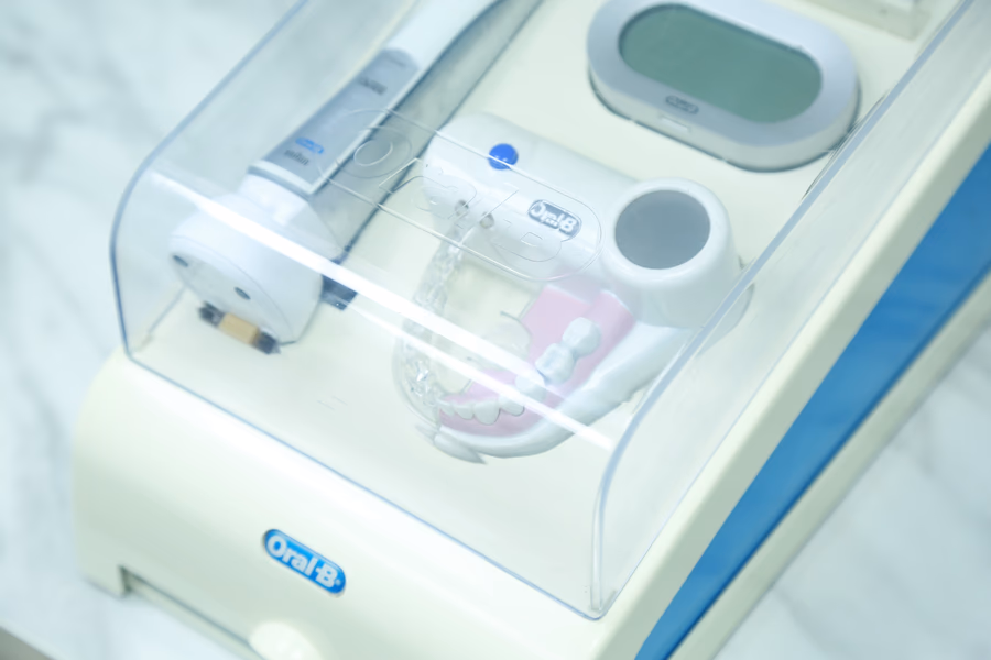 Oral-B dental care device inside a transparent protective case with an electric toothbrush handle and a dental model.