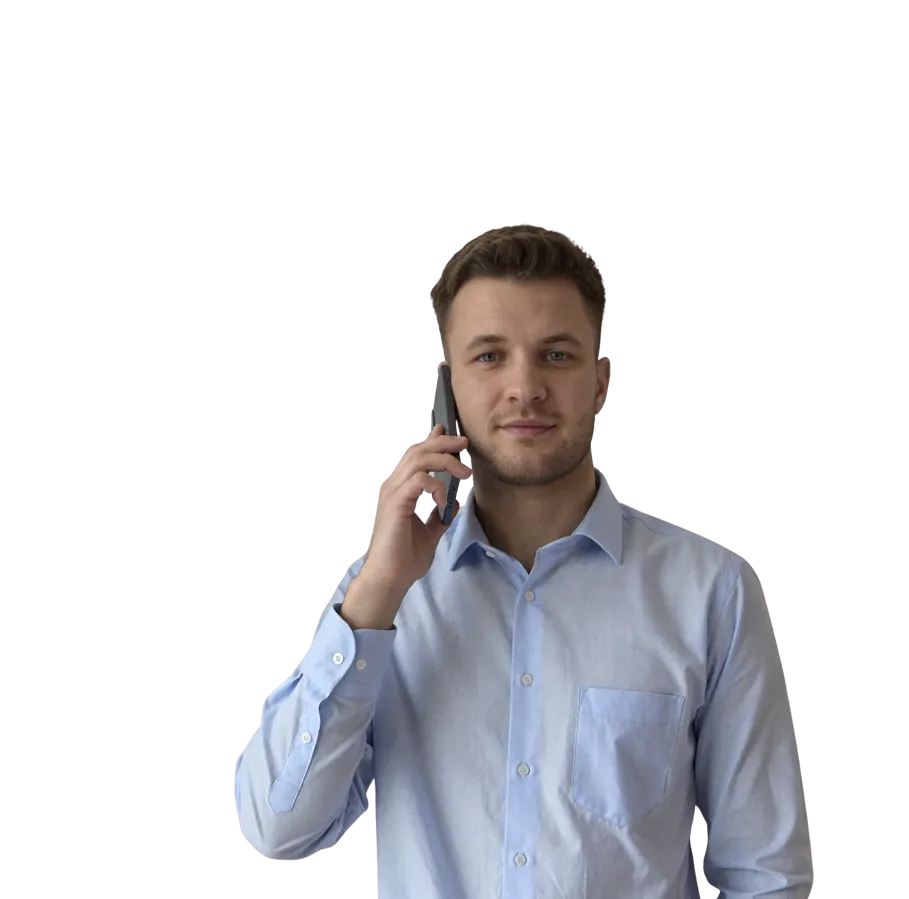Man in light blue shirt holding smartphone to his ear, looking at camera with a slight smile.