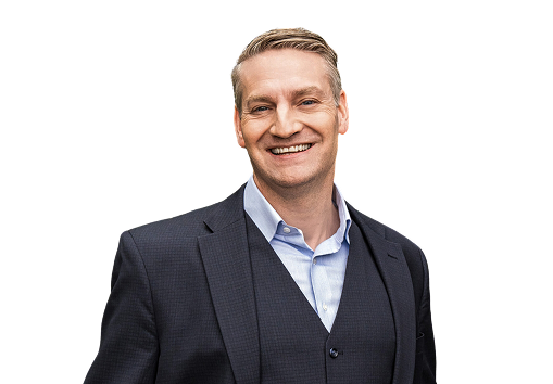 Smiling man in a dark suit and light blue shirt on a transparent background.