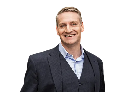 Smiling man in a dark suit and light blue shirt on a transparent background.