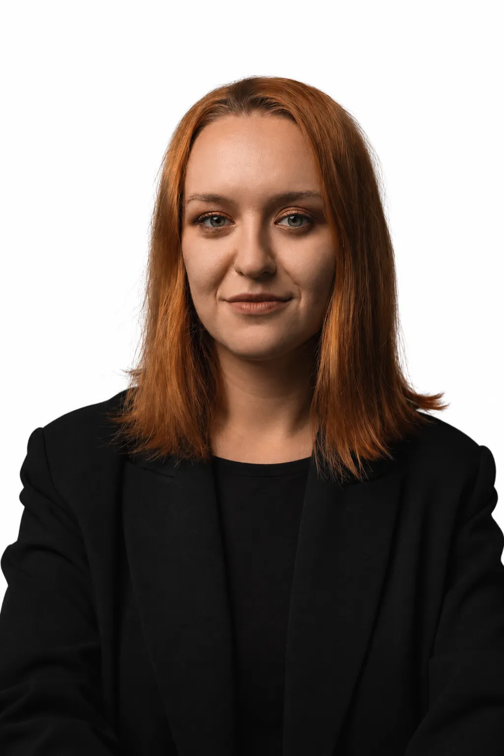 Portrait of a woman with straight shoulder-length red hair wearing a black jacket and black top, looking directly at the camera with a neutral expression on a white background.