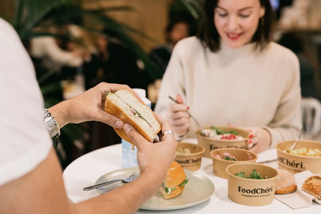 Des collègues déjeunent ensemble, avec sandwich et bols repas FoodChéri sur la table.