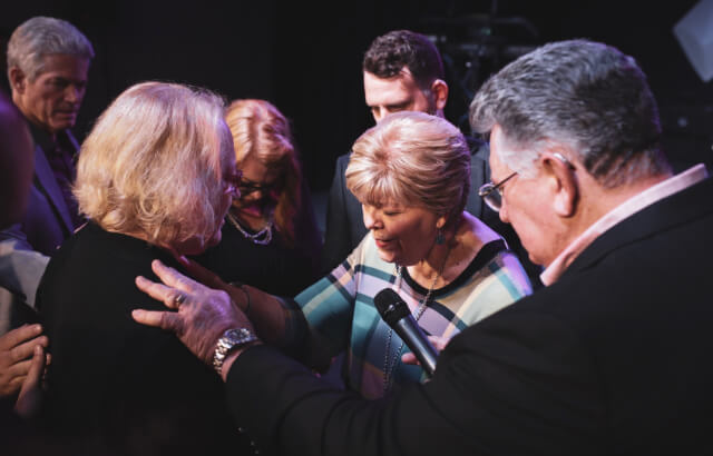 People are praying over their fellow member  at Faith Christian Fellowship