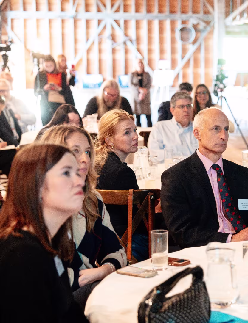 Adults attentively listening to a speaker at a conference or seminar in a well-lit room.