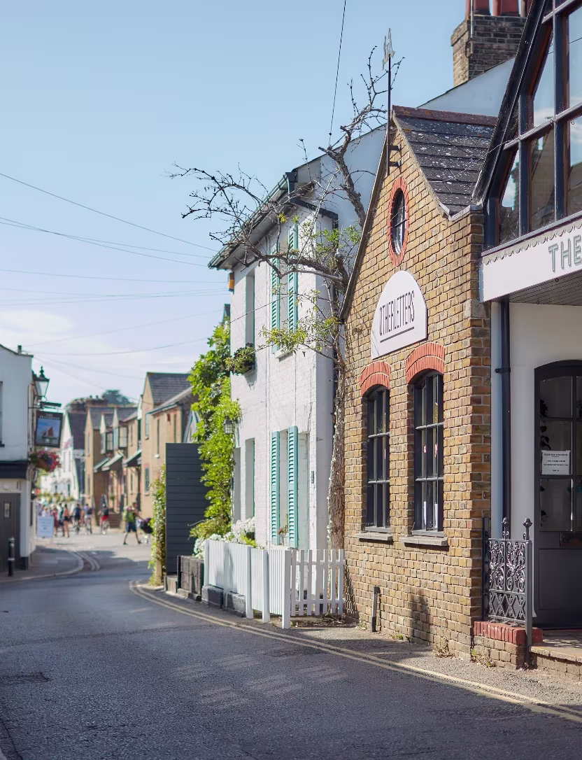 Sunny street with brick building labeled THE LETTERS and people walking in the background.