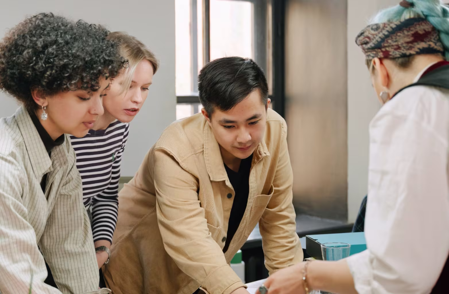 Four people gathered around a table, engaged in discussion with focused expressions.