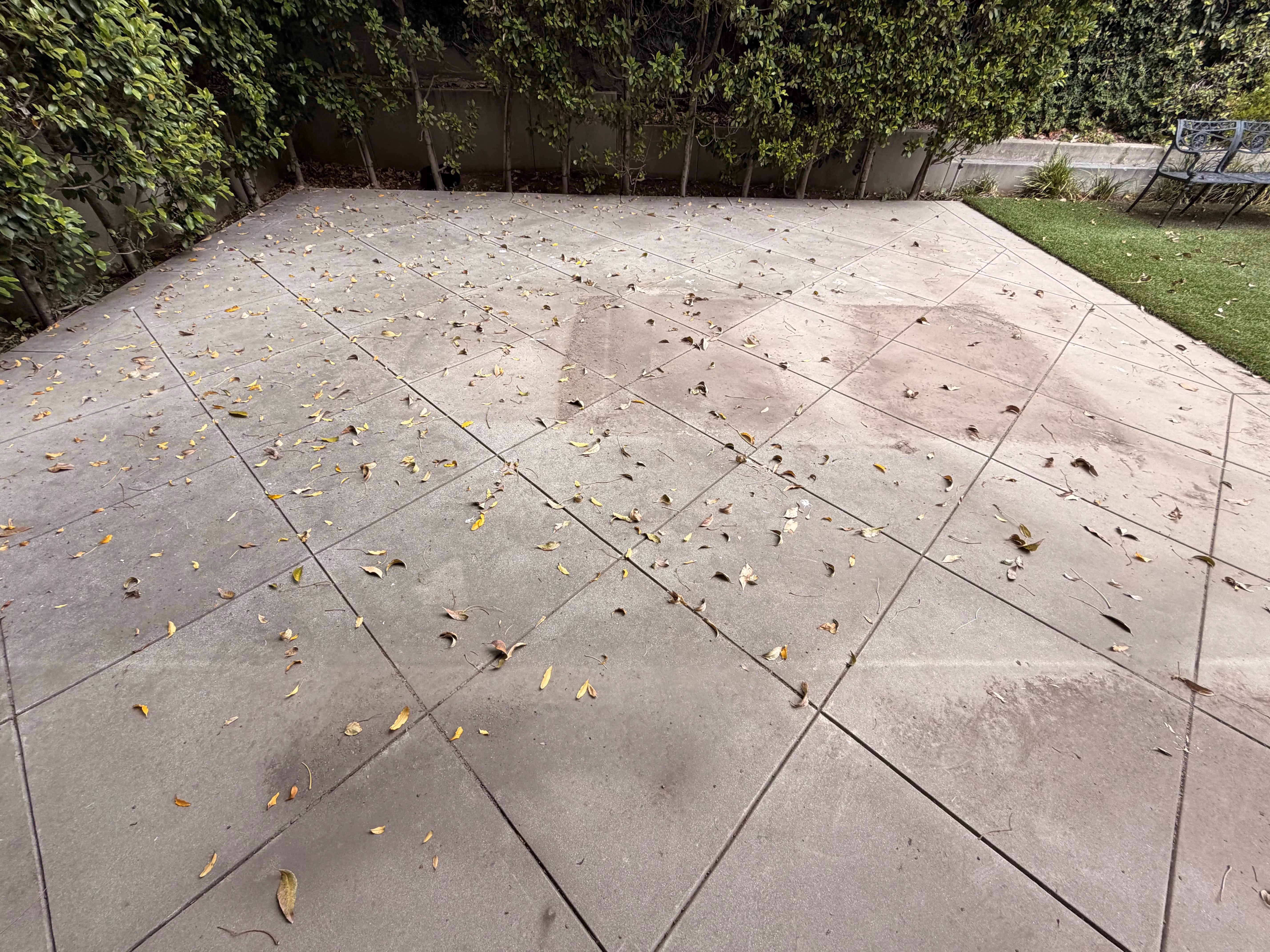 Dirty concrete patio with debris before pressure washing in Pasadena