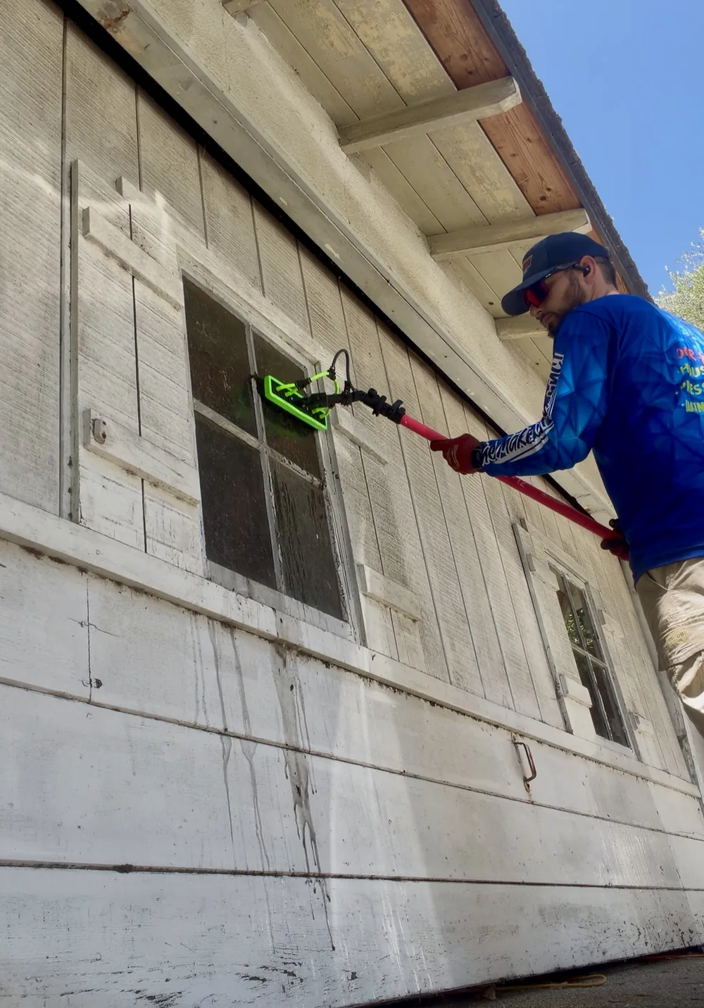 Close-up of a Rexterior technician using a water-fed pole brush head to clean a window