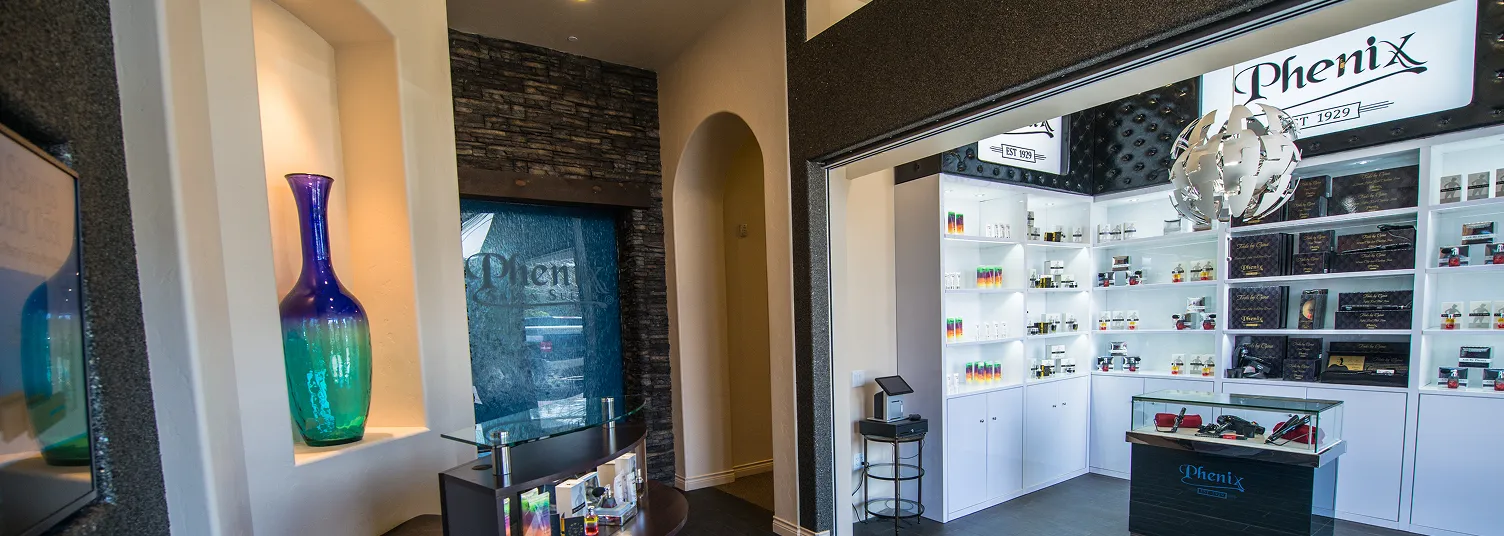 Modern retail interior with white shelves, glass display case, and Phenix cosmetics branding.