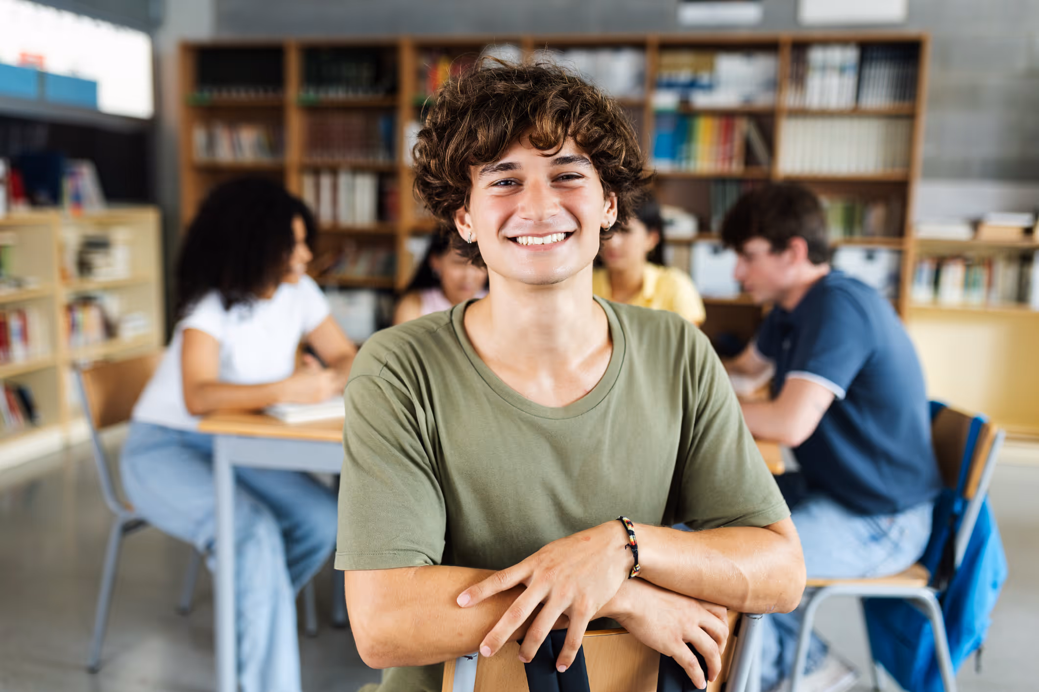Smiling teenage boy in a library, representing executive function coaching for planning, organization, and time management