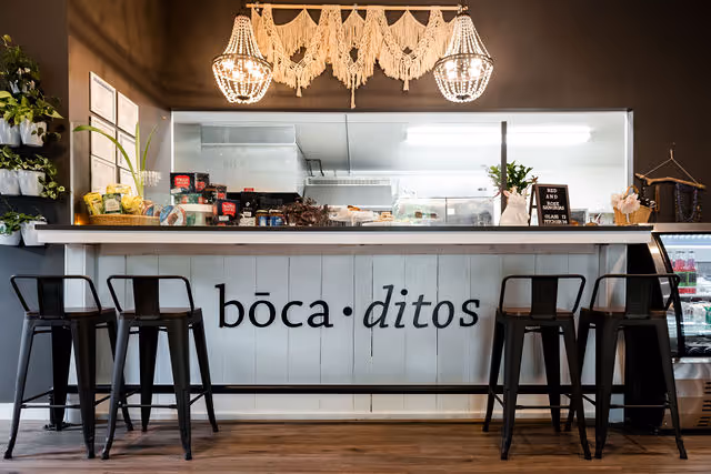 Interior of bocaditos café with a counter labeled 'boca.ditos' and four black metal stools.