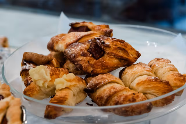 Plate of assorted golden brown croissants and pastries on a glass dish.