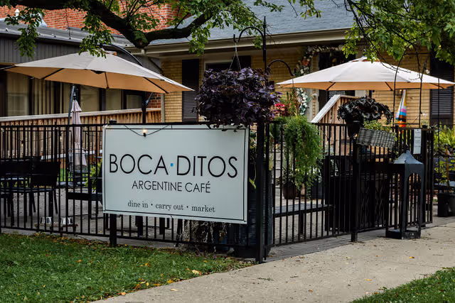 Outdoor patio of Bocaditos Argentine Café with umbrellas, tables, and hanging plants.