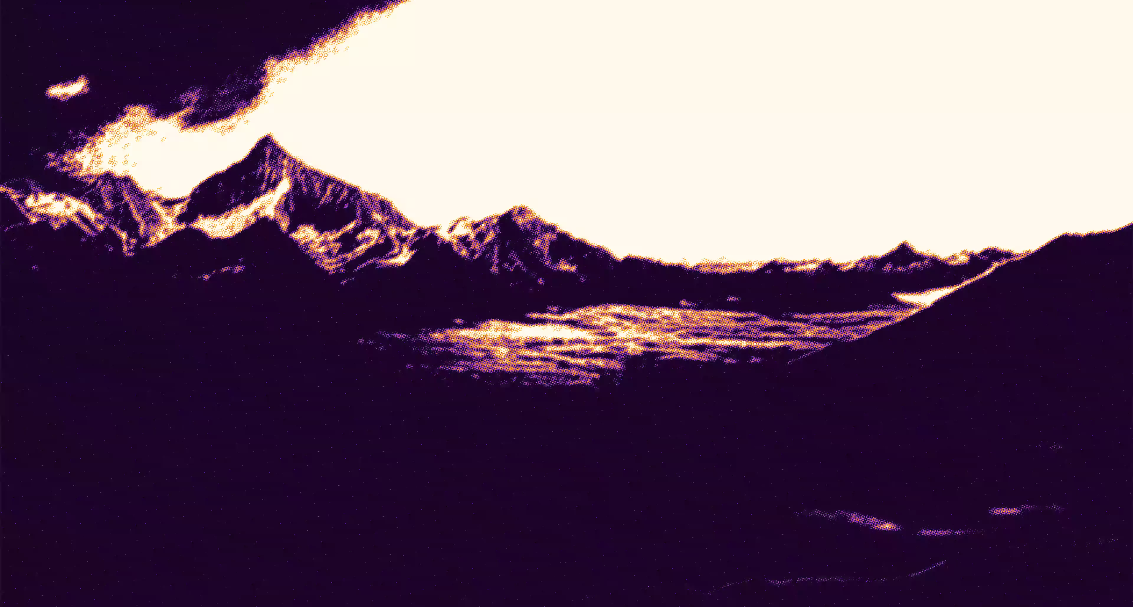 Dark mountain range with snow patches under a bright sky.