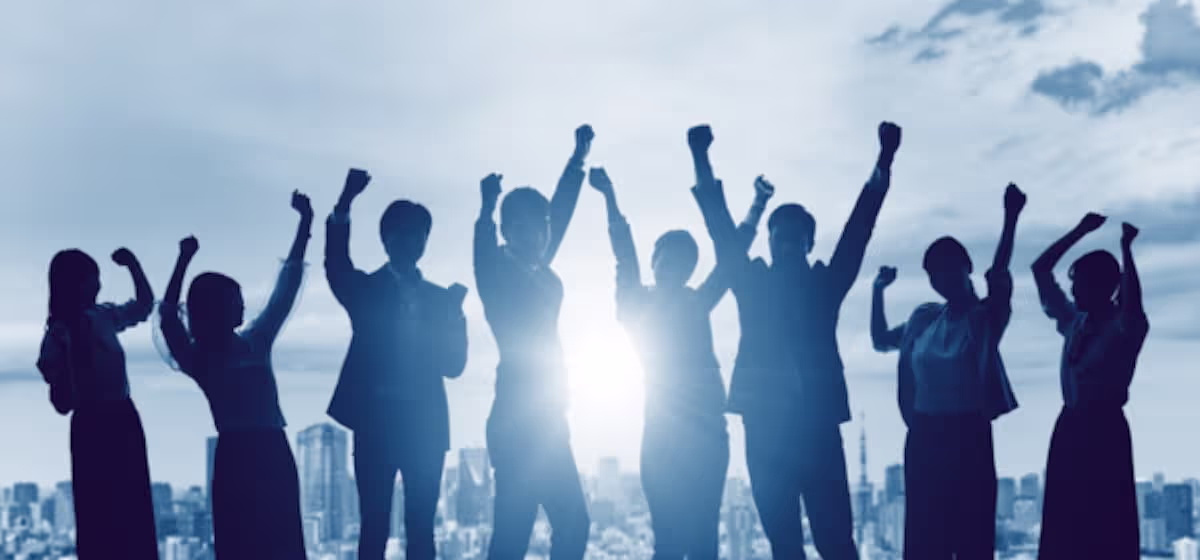 Group of happy professionals raising their hands in front of a city skylinec