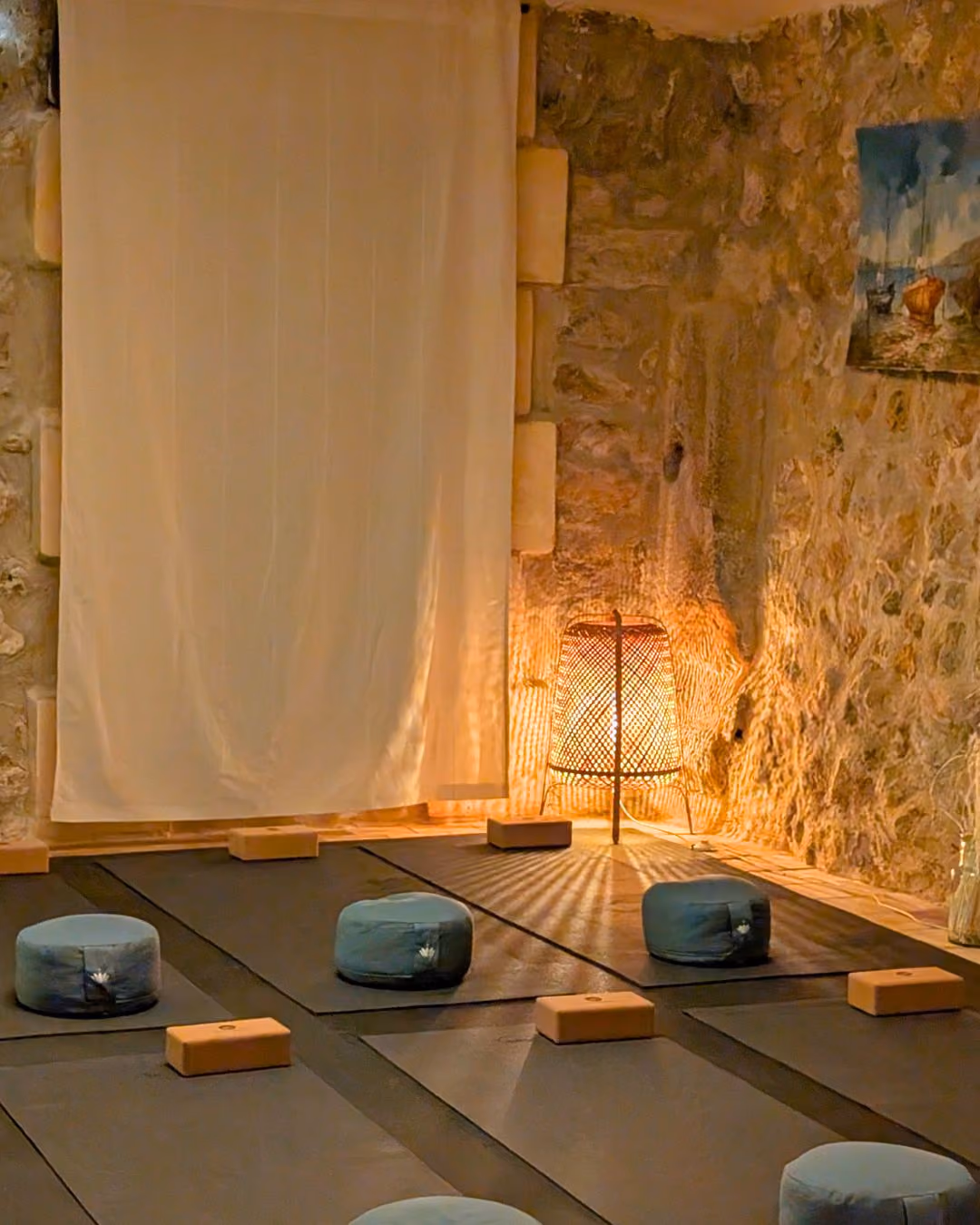 Cozy meditation room with floor cushions, yoga mats, wooden blocks, and a glowing wicker lamp, Finca Higo, Mallorca.